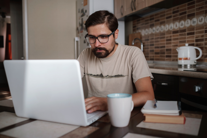 Portrait of handsome young man working on print on demand in home office, copy space